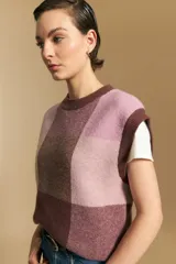 Chaleco tejido de punto con diseño de bloques a cuadros en tonos rosados, marrones y beige. Presenta cuello redondo y terminaciones acanaladas en cuello y sisas.