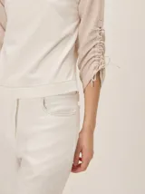 Remera de manga larga color blanco con cuello redondo y detalles fruncidos con lazos en las mangas.