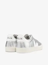 Championes Veja modelo Campo, confeccionados en cuero metalizado color plateado. Presentan el logo de la marca en los laterales en color blanco, cordones al tono y suela de goma en color crema.