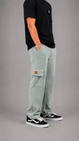 Pantalón tipo jogger cargo de corte holgado, color verde claro, con bolsillos laterales con solapa y etiqueta decorativa en cuero sintético.