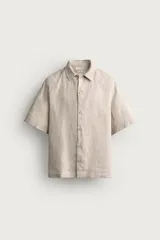 Camisa de lino color blanco, con ajuste relajado, cuello bowling, manga corta y cierre frontal con botones.