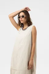 Vestido midi de silueta amplia y relajada, sin mangas, con escote redondo y costuras decorativas. Presenta una falda con corte y volumen.