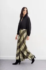 Pantalón de corte amplio y fluido, confeccionado en viscosa jacquard con hilos de lurex. Presenta un diseño de rayas diagonales con estampado de puntos dorados sobre fondo negro, cintura con elástico en la parte trasera y forrería a tono.