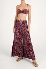 Pantalón de corte amplio con diseño de capas y cintura elástica con lazo frontal ajustable. Presenta un estampado animal print en tonos bordó y rosado.