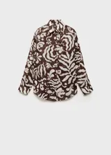 Camisa de algodón con estampado abstracto de hojas en tonos marrón y beige. Presenta cuello camisero, cierre frontal con botones y mangas largas con puños abotonados.