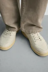 Zapatillas de piel estilo retro, color blanco crudo, con suela de goma con volumen en tono tostado y cierre de cordones.