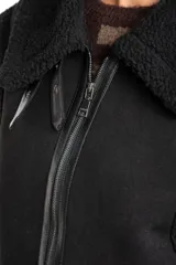 Chaleco estilo gamulán de color negro, con interior y detalles de corderito sintético. Presenta cierre frontal, cuello solapa y bolsillos laterales.