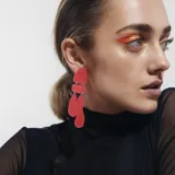Aros colgantes color rojo con piezas geométricas irregulares unidas por argollas plateadas.