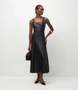 Vestido midi de corte estructurado confeccionado en cuero sintético (PU) color negro. Presenta escote cuadrado, breteles anchos y diseño con nesgas que aportan volumen a la falda. Incluye cierre posterior.