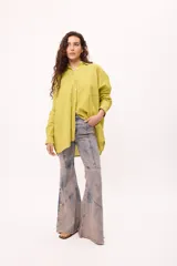 Camisa oversize a rayas verticales rosas y blancas, con cuello clásico, cierre frontal con botones y mangas largas.