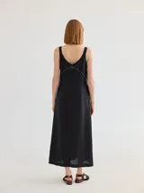 Vestido midi de corte recto y escote en V, con diseño bicolor que combina paneles en negro y tostado en forma de V invertida. Presenta costuras decorativas visibles en la unión de los colores.