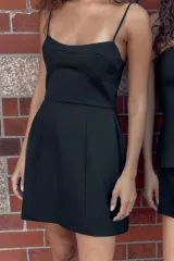 Vestido corto de corte ajustado con escote tipo bustier y tirantes finos. Presenta costuras verticales que definen la silueta y cierre posterior con cremallera oculta.