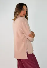 Sweater de punto gris con cuello alto, manga larga con puños acanalados y diseño holgado con costura central vertical.