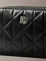 Cartera tipo bandolera Calvin Klein de diseño acolchado con patrón de rombos, color negro, cierre de cremallera y detalles metálicos plateados.