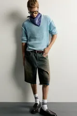 Bermuda de denim de algodón con efecto lavado desgastado en tonos marrones y azules. Tiene tiro medio, diseño de cinco bolsillos, pierna recta de corte holgado y bajo con acabado irregular. Cuenta con cierre frontal de cremallera y botón metálico.