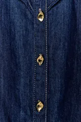Camisa de denim azul oscuro con cuello redondo y manga larga. Presenta un diseño con volantes en el pecho y hombros, puños con botones y cierre frontal con botones dorados.
