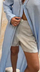 Short de lino en color celeste, con diseño de tiro alto, cierre frontal con botón a la vista y costuras decorativas verticales en el frente.