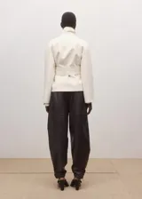 Chaqueta de mezcla de lana, poliéster y elastano color marfil, con solapas cruzadas, cuello alto y cinturón ajustable del mismo tejido. Cuenta con mangas largas y forro interior de viscosa.