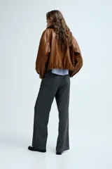 Pantalón de corte holgado y piernas rectas, confeccionado en tejido con textura de espiguilla. Presenta cintura elástica con cordón de ajuste, bolsillos laterales y bolsillos traseros decorativos.