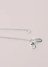 Collar largo de metal plateado con dije doble en forma de botella.