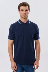 Remera polo de piqué azul marino, con cuello y puños de mangas cortas con ribete blanco en contraste, cierre frontal de dos botones y pequeño logo bordado en el pecho.
