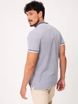 Remera polo de piqué de algodón melange color celeste, con cuello y puños en contraste blanco y azul, cierre frontal con botones y bordado pequeño en el pecho.