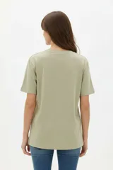 Remera de manga corta color blanco, de corte holgado con cuello redondo a la base y estampado frontal en tono bordó de un gato y un ovni en un paisaje desértico.