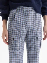 Pantalón de tiro alto con diseño de corte recto y ligeramente acampanado, confeccionado en tela con estampado de cuadros en tonos celestes, marrones y negros. Presenta bolsillos tipo cargo en la parte frontal con solapas y botones, y bolsillos traseros.