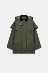 Trench de estilo encerado color verde militar con cuello de solapa en pana marrón, capucha extraíble y capa superior. Presenta cierre frontal con cremallera y botones a presión ocultos, bolsillos delanteros de plastrón con solapa y mangas largas con trabillas.