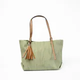Cartera tipo shopper color verde con textura tipo lino, doble asa de cuero sintético color camel con hebillas ajustables y detalle de borla de flecos de cuero sintético color camel.