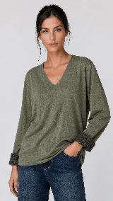 Buzo de manga larga con escote en V, confeccionado en tejido suave y liviano. Presenta un diseño relajado con puños que incluyen un detalle de estampado animal print visible al doblarlos.