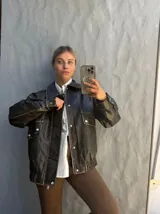 Campera de cuero estilo vintage en color negro con efecto desgastado, corte oversize, bolsillos frontales con solapa y cierre de botones metálicos.