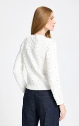 Sweater de punto calado en color blanco, con diseño de trenzas y detalles de cintas azul marino entrelazadas verticalmente en el frente. Presenta cuello redondo, mangas largas con puños acanalados y un pequeño lazo decorativo en el escote.