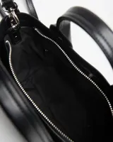 Cartera chica de símil cuero negro, tipo tote, con doble asa de mano y correa larga ajustable y desmontable. Cuenta con detalles de tiras verticales al frente y el logo de la marca en letras plateadas.