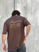 Remera marrón de corte amplio con estampado en la espalda con la palabra 'Perception' y otras frases en color dorado.