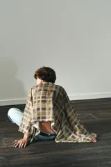 Capa corta con estampado a cuadros en tonos mostaza, marrón y blanco. Presenta un cuello redondo y mangas amplias tipo murciélago. Incluye un lazo o foulard integrado en el cuello para anudar.