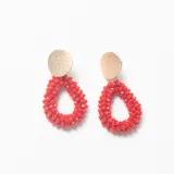 Caravanas con diseño de gota formado por pequeñas cuentas rojas y base circular de metal dorado con textura martillada.