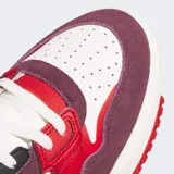 Championes Adidas Drop Step Low 2.0 de caña baja, con diseño inspirado en el básquet. Presenta una combinación de colores blanco, rojo y bordó, con las icónicas tres tiras laterales en negro. Confeccionados con exterior de gamuza y cuero sintético, cuentan con una suela de goma esculpida y forro interior de lycra para mayor comodidad.