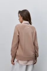 Cardigan de punto color beige, con escote en V, cierre frontal con botones oscuros y mangas largas con detalles de tejido en relieve.