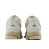 Championes urbanos New Balance modelo 2002R, color beige con detalles en gris y suela en tono arena. Confeccionados en una combinación de gamuza y malla, presentan el logo N característico en los laterales y tecnología de amortiguación en la entresuela.