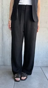 Pantalón negro de vestir con finas rayas verticales blancas, corte recto y tiro alto.