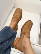 Mocasín de punta cuadrada confeccionado en piel con textura de pelo, color beige tostado, con detalle de antifaz en el empeine y costuras visibles en el borde.