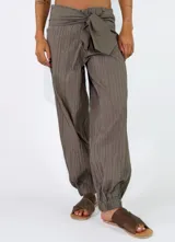 Pantalón beige con textura arrugada, de corte holgado estilo balloon con puños elásticos en los tobillos y cintura alta con faja y lazo ajustable.