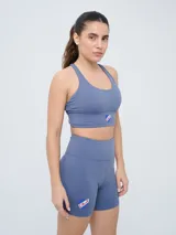 Top deportivo color gris azulado con diseño de espalda natación y el escudo del Club Nacional de Football en el centro.