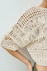 Top cropped de punto con diseño combinado de texturas, cuello redondo y mangas cortas amplias. Presenta una estructura calada con detalles de cintas verticales.