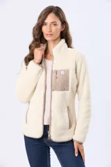 Campera de sherpa color beige con cuello alto y cierre frontal. Presenta un bolsillo frontal en el pecho de gamuza color arena con cierre y etiqueta decorativa, además de detalles en gamuza en los bordes.