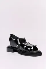 Sandalias negras de cuero charol con plataforma y taco bajo. Presentan tiras anchas con hebilla cuadrada grande en el empeine y tira de sujeción en el talón.