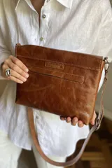 Sobre de mano color bordó en cuero charolado, con solapa frontal decorada con una piedra ágata natural engarzada. Incluye correa larga extraíble y cierre trasero.