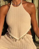 Top de punto color beige, con escote halter y espalda descubierta. Presenta un detalle de caracoles y cuentas en el bajo. Es de talle único y regulable.