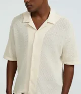 Camisa masculina de manga corta, color crema, con cuello bowling y calce boxy. El tejido presenta un efecto punto texturizado.